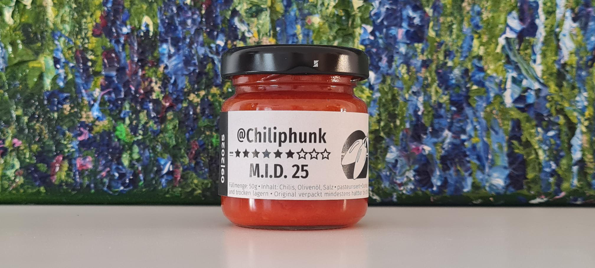 Ein einzelnes Glas Chiliphunk M.I.D.25 mit 6 Sternen, vor einem Blumengemälde.